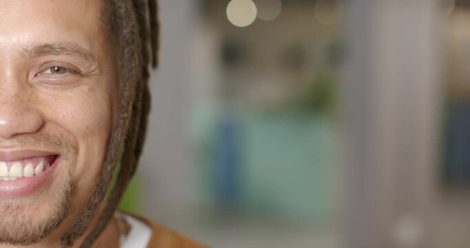 Adult African American man seeing camera, smiling, squinting in studio with bokeh light, copy space