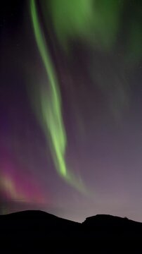 Vividly colorful aurora borealis at dusk Raudholar Iceland vertical format