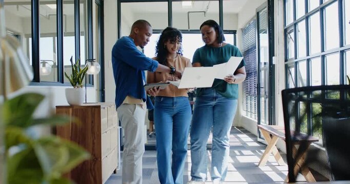 African American team walking office corridor, reviewing slides on laptop and folder for meeting