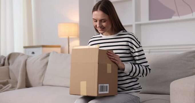 Woman opening parcel on sofa at home