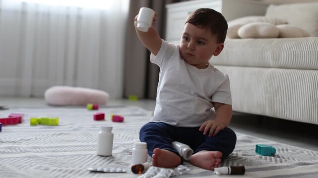 Child safety at home. Little boy playing with pills on floor indoors