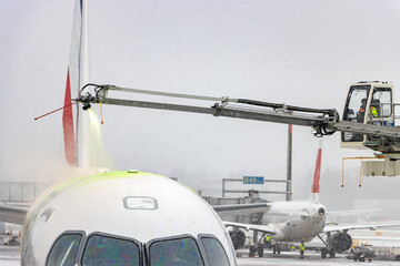 De-icing An Aircraft On The Ground With An Elevated Arm In Snow At The Airport