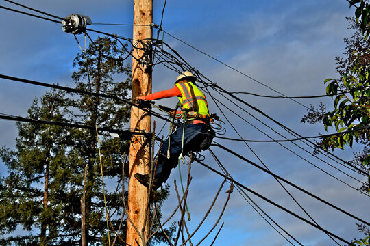 Telecommunications Linemen installing optical cables on telephone/utility pole as part of aerial telecommunications infrastructure