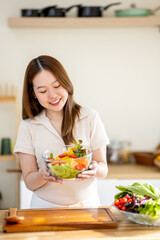 An Asian woman is making a salad in the kitchen. The concept is related to healthy eating and dieting.