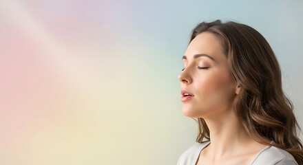 Fototapeta premium Woman meditating with eyes closed in serene pastel environment.