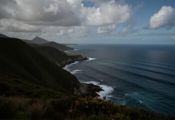 Naklejka premium Rauhe Küstenlandschaft mit steilen Klippen, kraftvoller Brandung und weitem Blick über den offenen Ozean unter wolkigem Himmel, natürliche Freiheit, Reise- und Naturgefühl