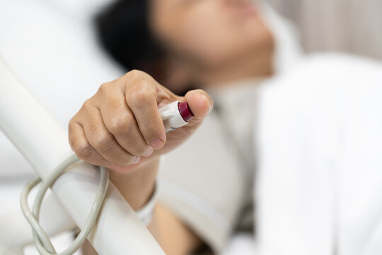 Close up woman patient hand pushing nurse call button inside bed in room hospital.Patient press red emergency button to calling nurse for help assistance remote control.Rescue safe life.