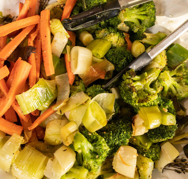 Close-up of roasted vegetables including carrots leeks and broccoli in serving dish