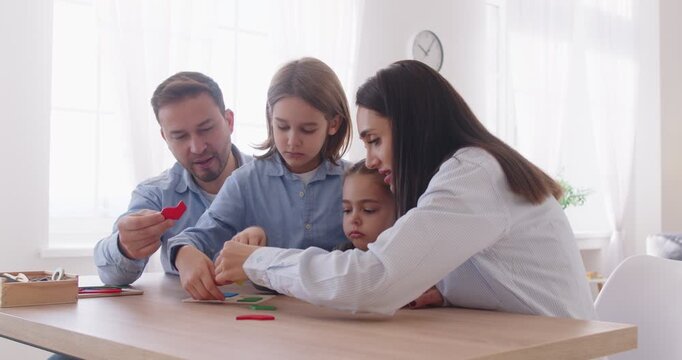 Family entertainment game, happy father, mother with little kids playing at home together, spending leisure time, children engaged in educational activity, wooden board game, developing motor skills