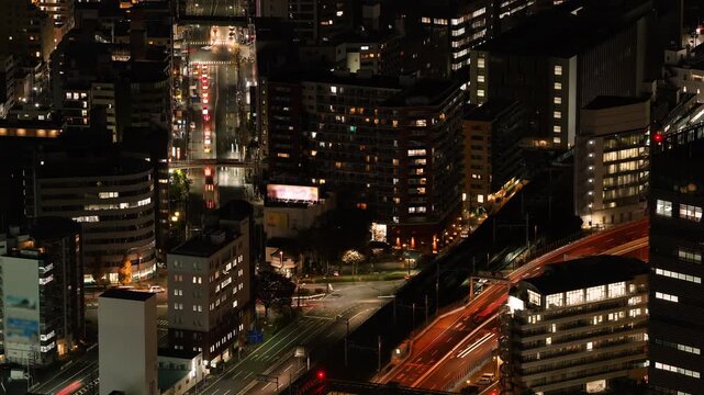 Aerial night view of Tokyo city intersection with traffic light trails.