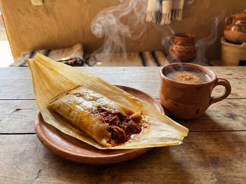 Authentic Mexican Cuisine: Handmade Tamale with Meat Filling and Clay Mug of Warm Beverage