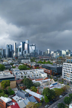 Aerial view of dark storm clouds and rain moving over a distant city skyline