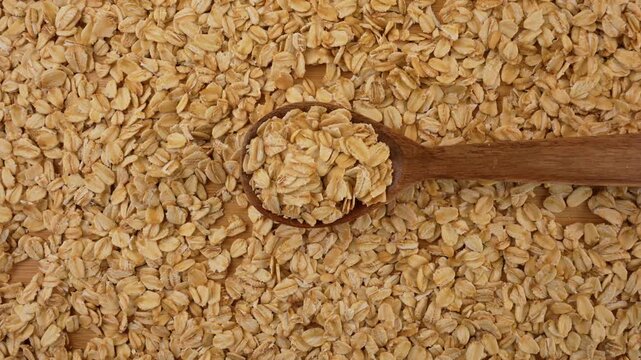 Dry uncooked oat flakes top view. Rolled oats in a wooden spoon. 