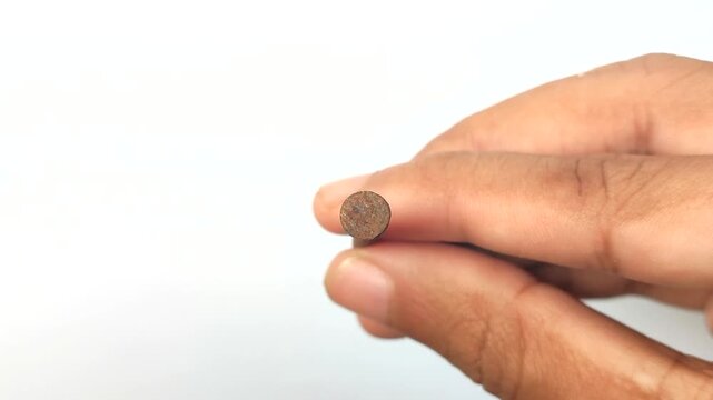 Man holding a rusty metal nail against a white background. Close-up of corroded old iron nail, symbol of tetanus risk, construction decay, and oxidation process