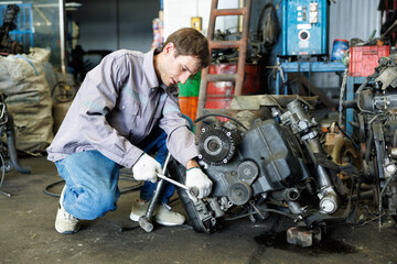 Mechanic is working diligently in a cluttered workshop surrounded by auto parts