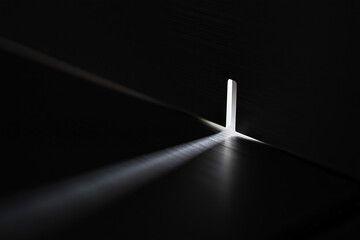 Bright beam of light shining through a crack in a dark doorway