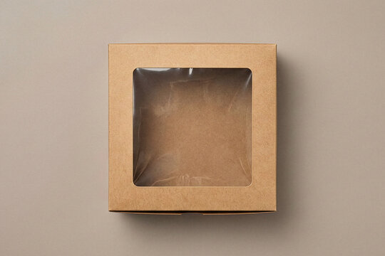 Top view of square brown cardboard cake box with clear plastic window on top