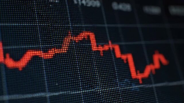 Financial data graph showing downward trend on screen with red line and grid background from close-up viewpoint