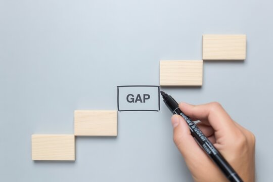 Hand drawing the word gap between wooden blocks on a gray background, symbolizing business strategy and problem solving