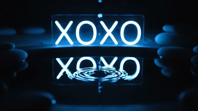 A high-contrast, close-up shot of the glowing electric blue neon xoxo sign reflecting in dark water, where ripples are caused by a falling droplet, setting a mysterious mood.