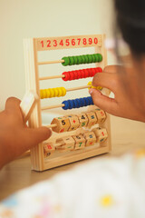 Child learns numbers with wooden abacus at home