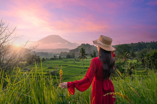 A female tourist with a view of the sunrise over a volcano in Indonesia.
