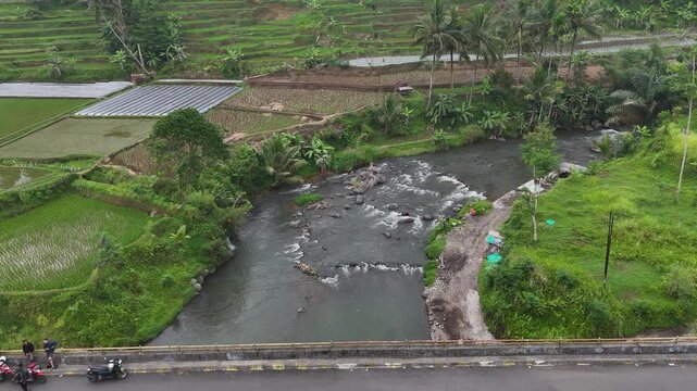 Water flows through a concrete check dam beneath a small bridge, helping regulate river discharge and prevent erosion.