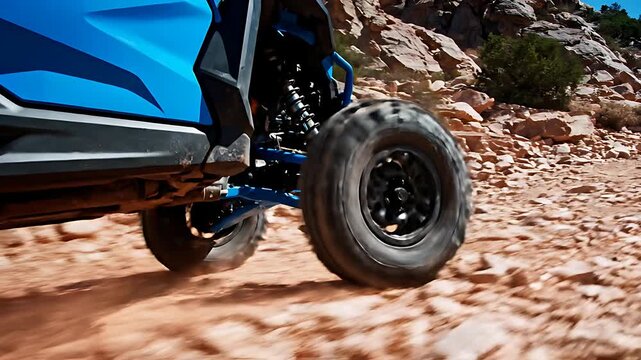 Rugged blue all-terrain vehicle suspension system aggressively tackles challenging, rocky desert trails with powerful motion blur showcasing speed and durability.