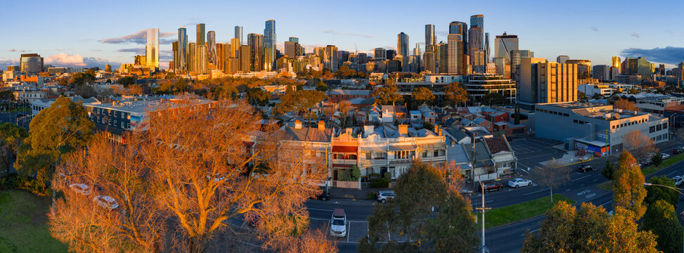Aerial panorama view of golden evening light on suburban terrace houses and a distant city skyline