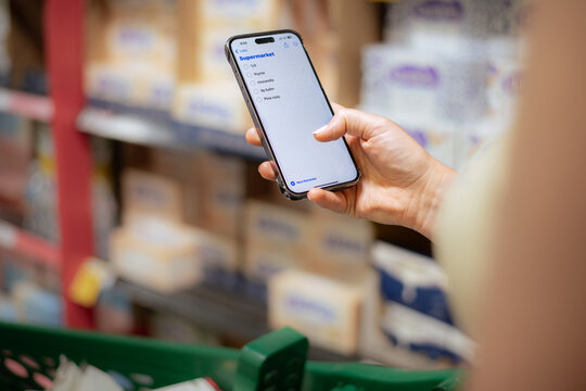 woman at the supermarket using phone shopping list