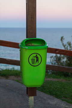 Green rubbish bin mounted on wooden pole in public park