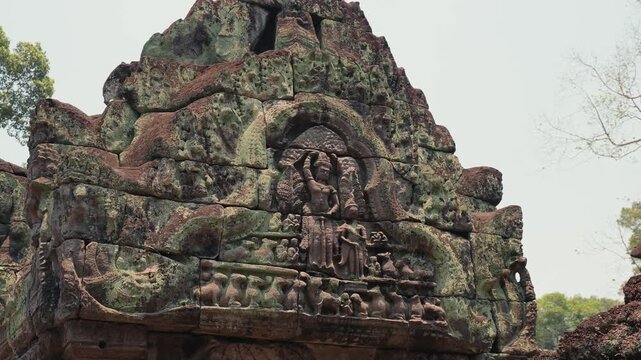 View of ancient stone pediment with carved deity relief and weathered surface at Angkor Wat in Cambodia, showing historic architecture, sacred art, and heritage