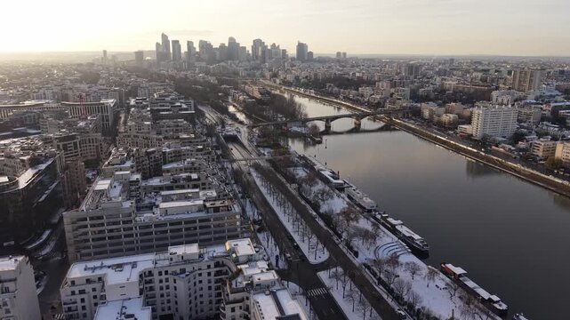 Aerial drone wide view of Seine River with historic bridges and urban landscape during winter morning, showing snow-covered streets and Parisian cityscape, Paris, France