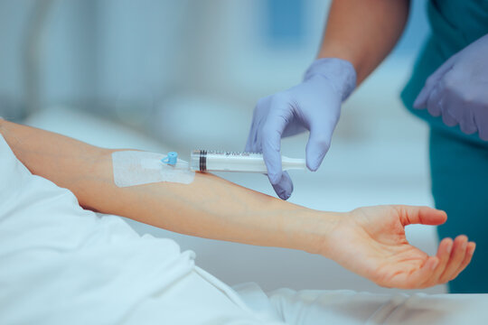 Nurse Uses Syringe to Inject a Concentrated Dose of Medication into an IV. Healthcare professional administers a direct IV injection through a needleless access port 