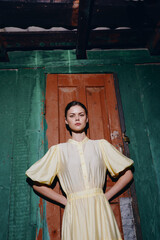 woman dress fashion pose doorway vintage yellow wall stands confidently in front of a weathered door with a green backdrop creating a striking fashion portrait © SHOTPRIME STUDIO