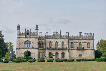 Fototapeta premium Mansion manor historic architecture stone facade estate landscape with detailed windows and turrets isolated building on lawn under cloudy sky preserved exterior masonry