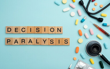 Fototapeta premium Decision Paralysis word on wooden blocks with prescription pills and stethoscope on sky blue background. Mental health disorder treatment concept, psychological care, therapy, 