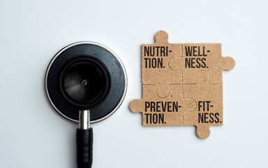 stethoscope and puzzle with the words Wellness, Nutrition, Fitness and Prevention. four words commonly associated with health.