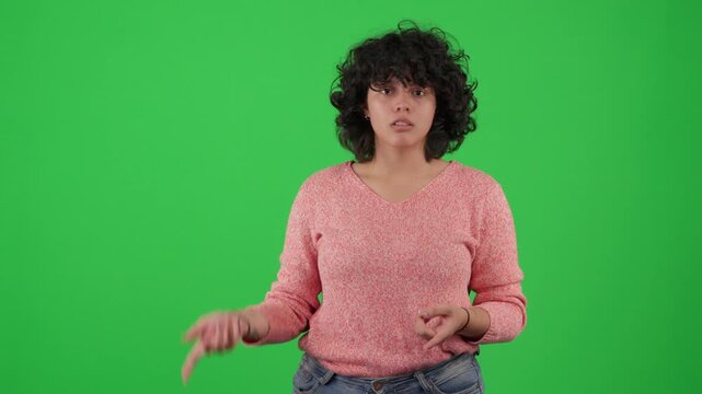 Young woman talking and gesturing toward the camera on a green screen background