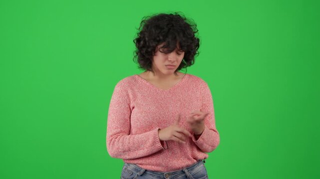 Horizontal studio shot of a young woman with curly hair acting against a chroma key green screen. 