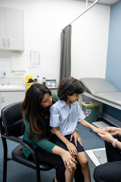 Young boy sitting on mothers lap inside examination room