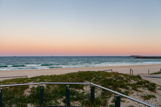 Sand dunes and railing to beach and ocean with dusk colour gradient in evening sky