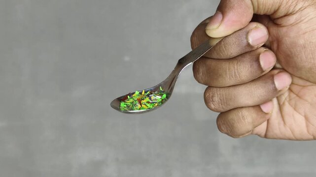 Closeup of person hand holding spoon with microplastic particle pieces or fragments. Harmful Micro or macro plastic pollution, contamination, consumption or exposure in human food awareness concept.