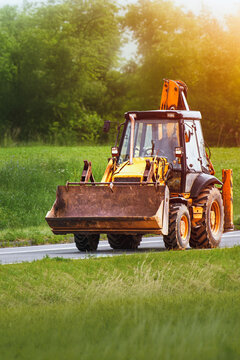 Yellow backhoe loader on quiet rural road