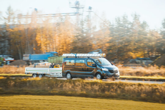 Commercial van towing utility trailer on road