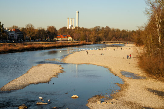 Scene at the Flaucher in Munich, known for its extensive gravel banks. In the background, the Flauchersteg, a striking wooden bridge for pedestrians that crosses the Isar River.