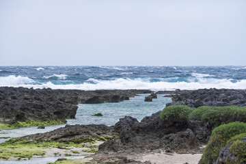 アニメ風の荒れる海と珊瑚礁の海岸、白い波が打ち寄せる冬の海背景素材（コピースペース・デザイン素材）
