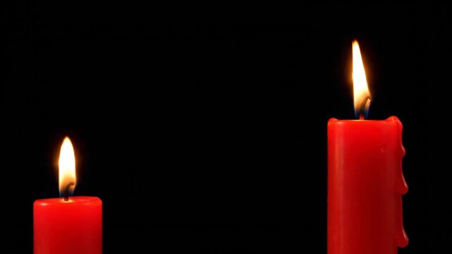 Two red candles burning brightly against a dark background.
