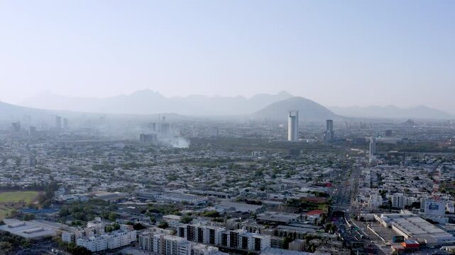 Drone view of Monterrey City with smoke in the background due to city disturbance. Polluted air above the city.