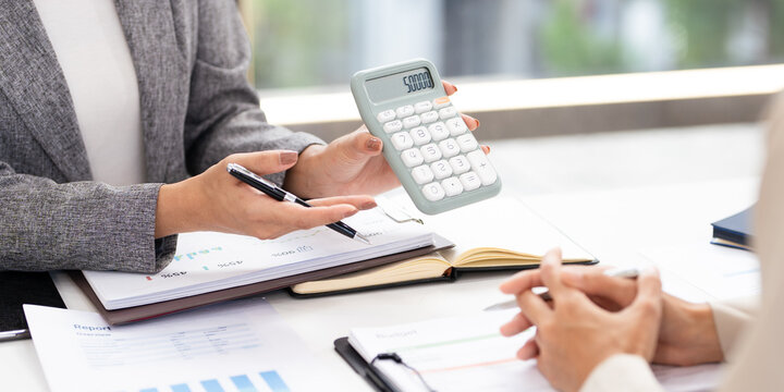 Smiling asian businesswomen financial advisor explaining financial result showing calculator to client or Collegue  in meeting.
